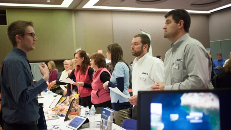 Job seekers queueing at recruiter booths at a career fair, the volume hiring AI tools for HR target